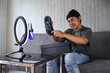 © Gatot - Smiling Asian male influencer or shoes seller showing his product to online followers through smartphone. Product review video