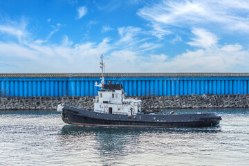 Wall Mural - The tugboat passes in the strait of the city port.