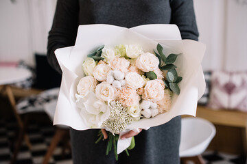 Wall Mural - Very nice young woman holding big and beautiful bouquet of fresh roses, carnations, cotton, eucalyptus flowers in pastel pink colors, cropped photo, bouquet close up