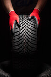 Fototapeta Mapy - Car tire service and hands of mechanic holding new tyre on black background with copy space for text