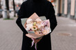 Very nice young woman holding big and beautiful bouquet of fresh roses, eustoma, carnations flowers in pastel colors, cropped photo, bouquet close up