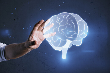Poster - Close up of male hand holding glowing human brain hologram on blurry wall background. Neurology research and artificial intelligence concept.