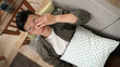 © PRPicturesProduction - view from above of a sleepy asian young man lying on sofa after yawning rubbing eyes at home.