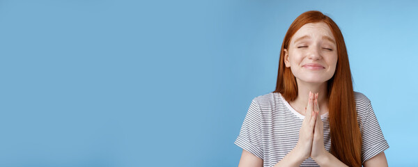 Wall Mural - Girl making wish bottom heart willing dream come true press palms together pray supplicating close eyes smiling sincere belief desire fulfill anticipating miracle, standing blue background