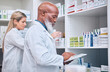 © J Bettencourt/peopleimages.com - Pharmacy, stock and digital tablet for inventory by man and woman checking medicine and packing shelves. Pharmacist, senior man and online search on device app for information, prescription and pills