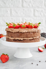 Naked chocolate cake with cream and fresh strawberries on top. Rustic style. Selective focus. Copy space.