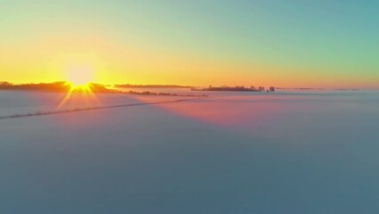 Wall Mural - Glowing golden sunset on the horizon of an empty snowy landscape of rural farmland fields - aerial view