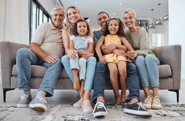 Love, interracial and family on sofa, grandparents and children relax, portrait and happy together. Grandmother, grandfather and girls with mother, father and bonding in living room, smile or weekend