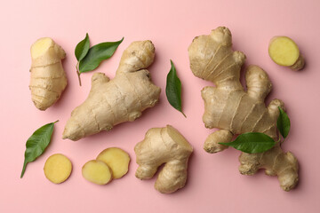 fresh ginger with green leaves on pale pink background, flat lay