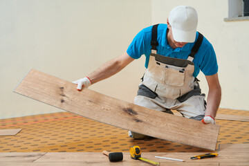 vinyl floor installation. Close-up hands of worker at home flooring renovation.