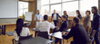 © Studio Romantic - Panoramic view of people office staff standing and sitting at desks in modern office talking during break on corporate team training. Multiracial group men and women discussing seminar or masterclass.