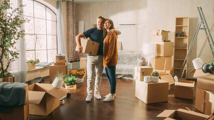 Family New Home Moving in: Happy and Excited Young Couple Enter Newly Purchased Apartment. Beautiful Family Happily Embracing, Imagining Future. Modern Home Ready for Decorations