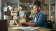 © Gorodenkoff - Diverse Male and Female Warehouse Inventory Managers Talking, Using Laptop Computer and Checking Retail Stock. Rows of Shelves Full of Cardboard Box Packages in the Background.