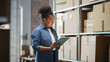 © Gorodenkoff - Portrait of a Worker Checking Inventory, Writing in Tablet Computer. Black Woman Working in a Warehouse Storeroom with Rows of Shelves Full of Parcels, Packages with Orders Ready for Shipment.