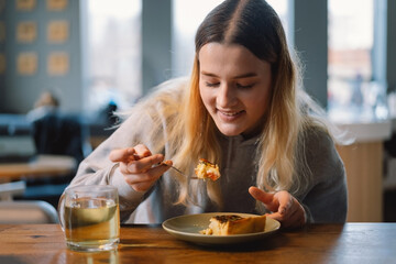 Young teengirl eating quiche with fresh vegetable and looking on smartphone and breakfast of wellness lifestyle at cafe. Cafe city lifestyle.