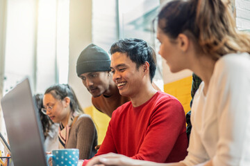 Young co-workers multiethnic team planning a new startup - Happy computer programmers working on a new project in creative coworking office - Bright filter with focus on asiatic man face