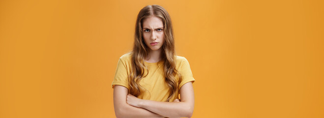 Girl mad like devil. Portrait of angry bothered and offended hateful young woman looking from under forehead frowning and sulking crossing arms against chest in defensive pose, scorning offender