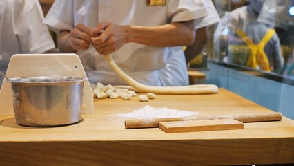 Work of chef with the dough at the table in the kitchen, the cook divides the dough into portions for making buns and other baked goods for serving in the restaurant. Cooking dough in a restaurant.