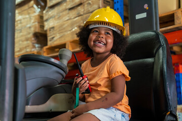 three-year-old African-American girl in an engineer's helmet smiling happily drives a forklift as an engineer in a factory.