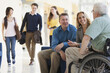 © Designpics - People walking and talking in an airport lounge, one with Muscular Dystrophy