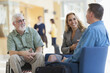 © Designpics - Passengers talking to each other in an airport lounge, one with Muscular Dystrophy
