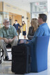 © Designpics - Passengers talking to each other in an airport lounge, one with Muscular Dystrophy