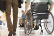 © Designpics - Man with Muscular Dystrophy in a wheelchair walking with another passenger in a corridor of an airport