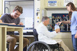 © Designpics - Professor with a spinal cord injury in a wheelchair working with students in an engineering lab filling container with distilled water