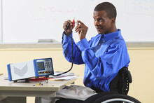Engineering Student In Wheelchair From Spinal Meningitis Connecting Capacitor To LCR Impedance Meter