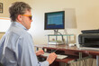 © Designpics - Man with congenital blindness using assistive technology at his computer to listen