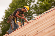Carpenter Using Safety Strap On The Roof Of A House Under Construction