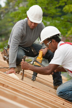 Carpenters Using A Sawzall And A Pry Bar On The Roof Of A House Under Construction