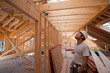 © Designpics - Hispanic carpenter looking at roof on upper floor at a house under construction