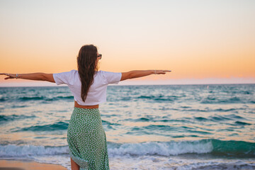 Young happy woman on the beach enjoy her summer vacation. Girl is happy and calm in her stay on the beach