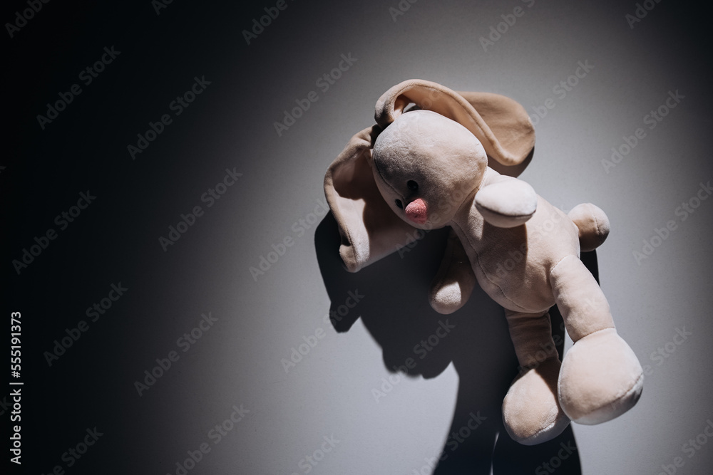 Teddy rabbit is alone in a dark room. Child abuse, solitude and ...