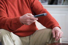 Midsection of a man holding a remote control.