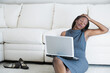 © Designpics - Middle-aged woman leaning against a couch and holding a laptop on her lap