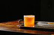cognac passion fruit juice and lemon juice cocktail glass detail shot on a bar table with black background