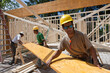 © Designpics - Carpenters lifting a laminated beam at a construction site