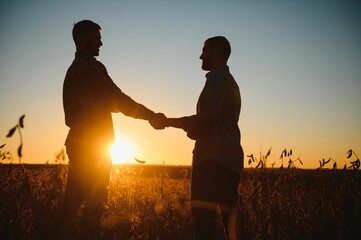 portrait of two farmers in a field examining soy crop