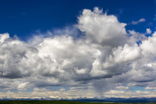 Large Storm Clouds With Blue Sky And The Rocky Mountains In The Distance; Calgary, Alberta, Canada