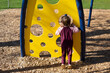 © Designpics - Preschooler girl stands looking through a hole of a play structure at a playground; North Vancouver, British Columbia, Canada