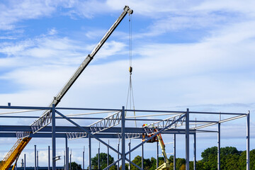 Canvas Print - New building steel framework assembly using telescopic boom crane and self propelled lift platform