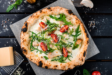 Canvas Print - Italian pizza with cheese parmesan, chicken, arugula, cherry tomatoes and spices on a thick dough from oven.