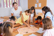 © JackF - Teacher and group of kids playing board game in school after lessons. Children having fun playing interesting game.