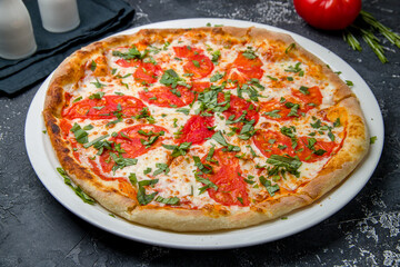 Wall Mural - Italian pizza Margherita with cheese. and tomatoes on dark table