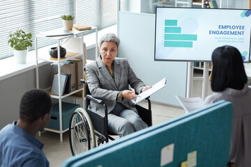 High angle portrait of senior businesswoman using wheelchair while giving presentation in office