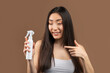 Hairstyle cosmetic concept. Korean lady holding bottle with hair spray, recommending new beauty product