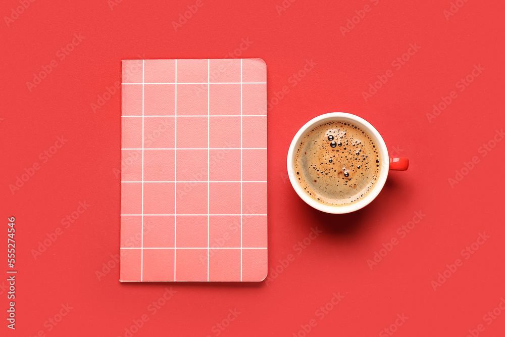 Cup of coffee and notebook on red background