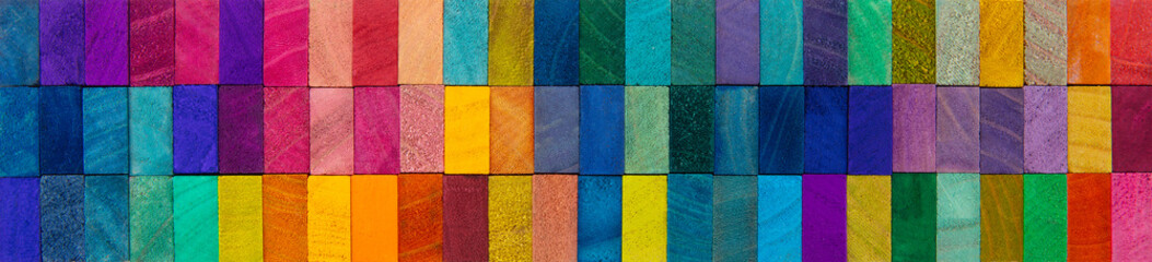 Header image or cover image for something creative or diverse. Wide format background of wooden blocks. A Spectrum of multi-colored wooden blocks aligned. 